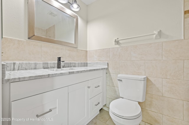 bathroom featuring vanity, toilet, and tile walls