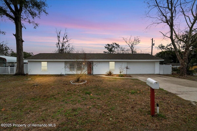 single story home featuring a garage and a yard