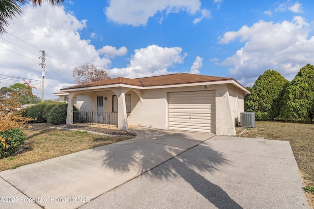 view of front of property with a porch, a garage, a front lawn, and central air condition unit