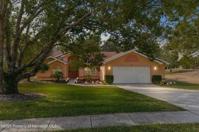 view of front of home featuring driveway, a garage, a front lawn, and stucco siding