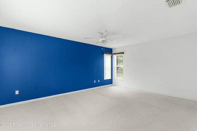 carpeted spare room featuring visible vents, ceiling fan, and baseboards