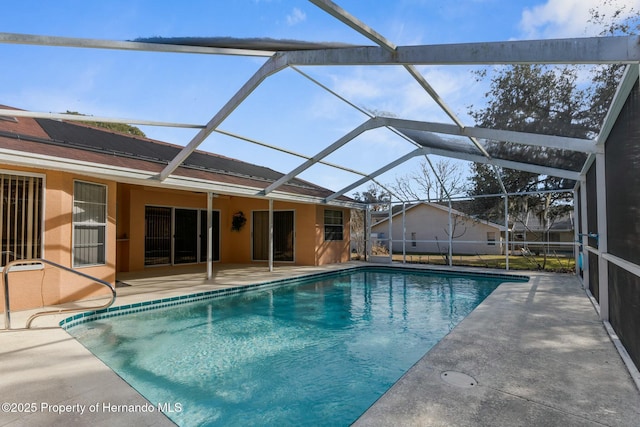 pool featuring glass enclosure and a patio area