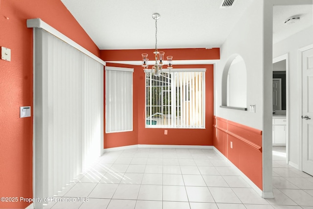 unfurnished dining area with light tile patterned floors, baseboards, and a notable chandelier