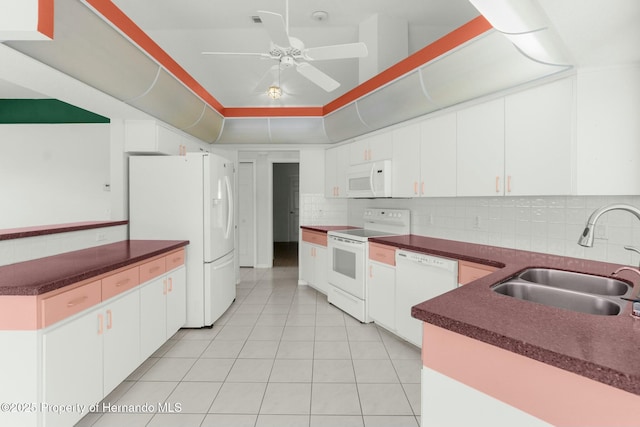 kitchen with white appliances, a sink, white cabinets, tasteful backsplash, and dark countertops