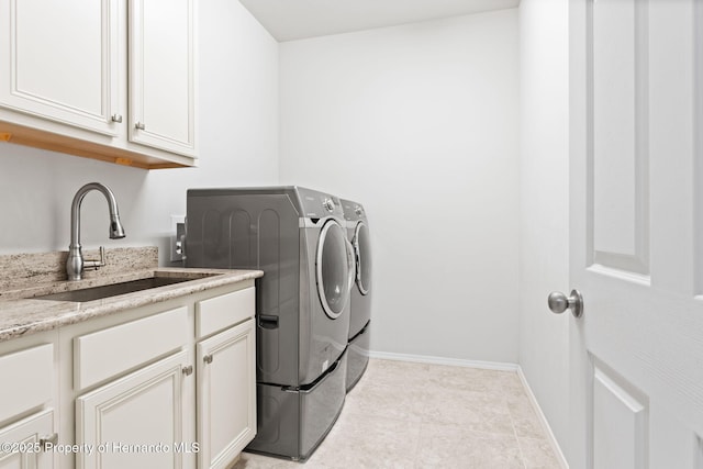 clothes washing area featuring separate washer and dryer, sink, cabinets, and light tile patterned flooring