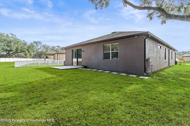 rear view of property featuring a patio and a lawn