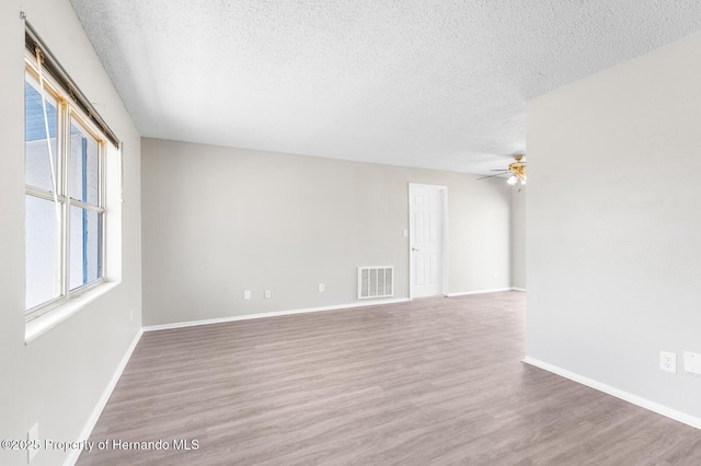 unfurnished room with ceiling fan, hardwood / wood-style flooring, and a textured ceiling