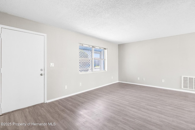 unfurnished room with hardwood / wood-style floors and a textured ceiling