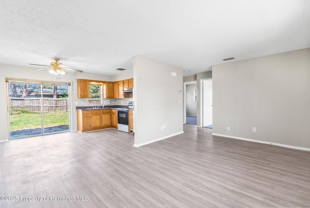 kitchen with sink, a textured ceiling, electric range oven, light wood-type flooring, and ceiling fan