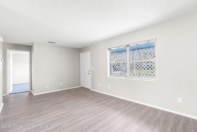 empty room with hardwood / wood-style flooring and a textured ceiling