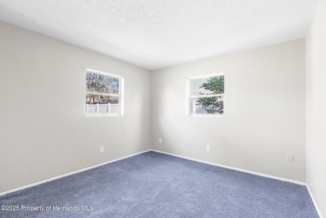 carpeted empty room featuring a textured ceiling