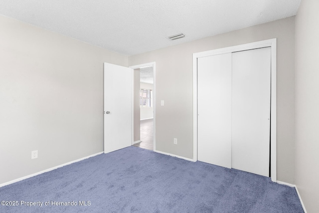 unfurnished bedroom with a closet, carpet, and a textured ceiling