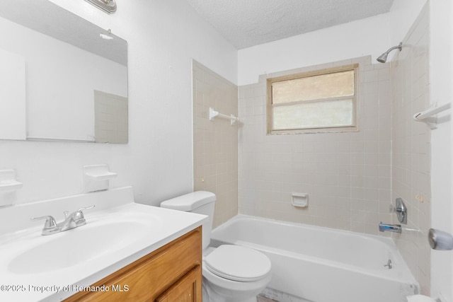 full bathroom featuring vanity, tiled shower / bath, toilet, and a textured ceiling