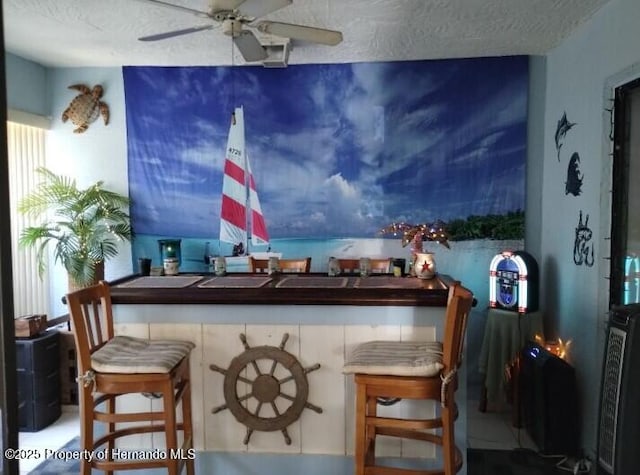 bar featuring ceiling fan and a textured ceiling