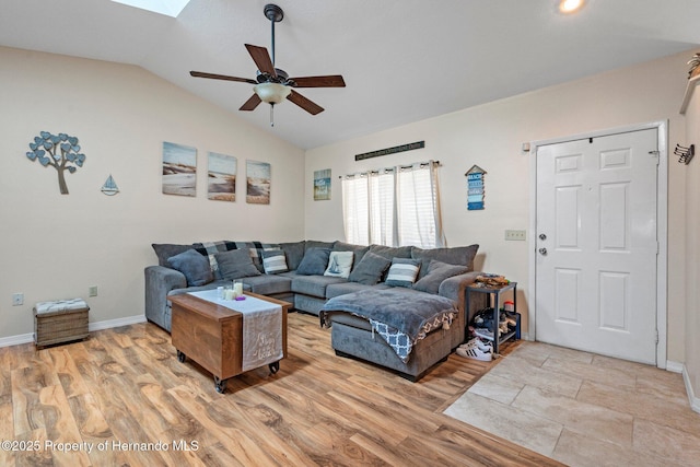 living room with ceiling fan, lofted ceiling with skylight, and light hardwood / wood-style flooring