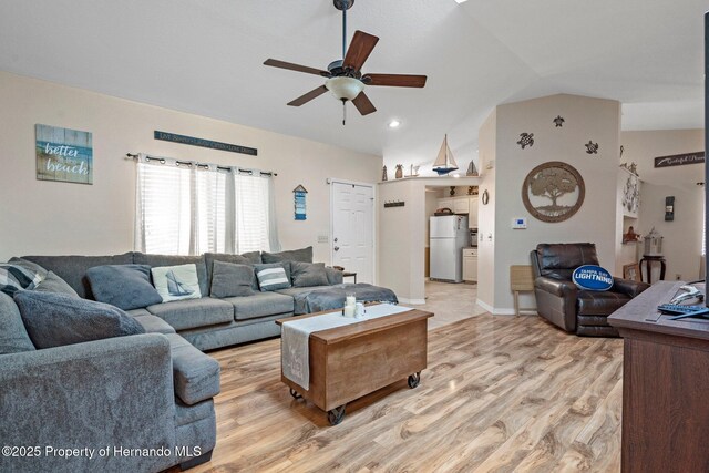 living room featuring light hardwood / wood-style flooring, vaulted ceiling, and ceiling fan