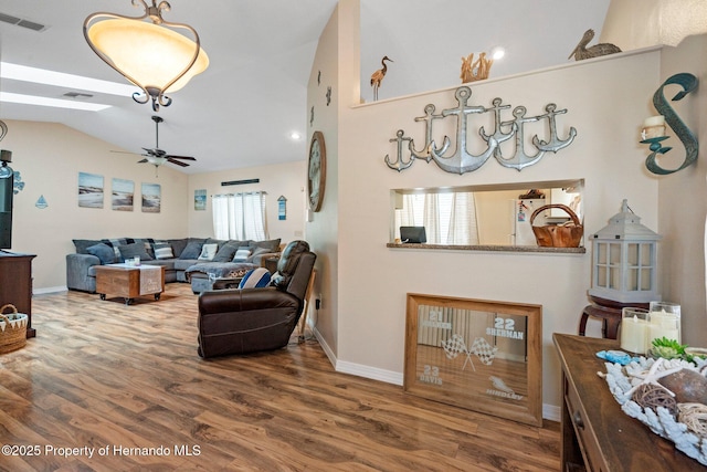 living room with hardwood / wood-style flooring, ceiling fan, and vaulted ceiling