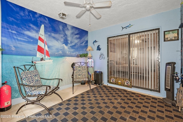 sitting room featuring tile patterned flooring, ceiling fan, a water view, and a textured ceiling