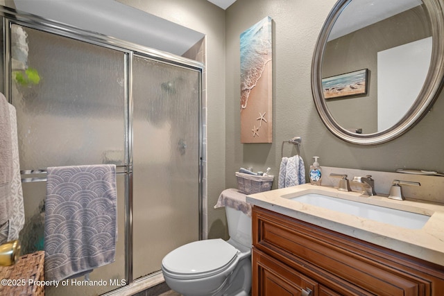 bathroom featuring vanity, a shower with shower door, and toilet