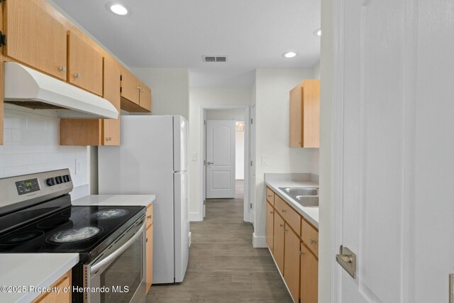 kitchen featuring sink, light brown cabinets, electric range, light hardwood / wood-style floors, and decorative backsplash