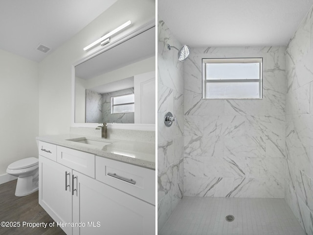 bathroom featuring vanity, hardwood / wood-style floors, toilet, and tiled shower