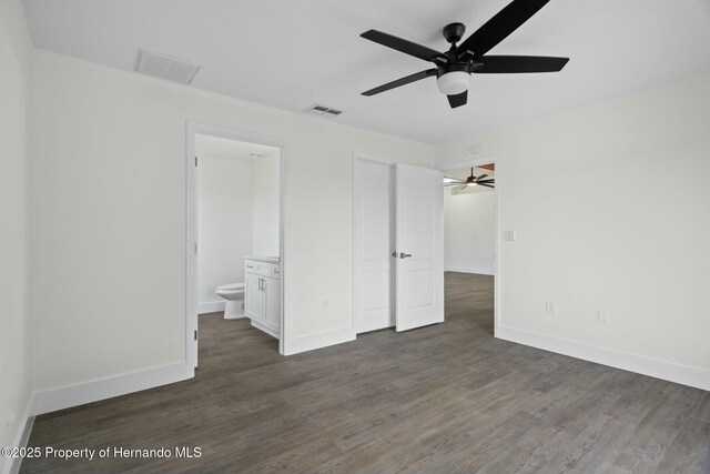 unfurnished bedroom with dark wood-type flooring, ceiling fan, and connected bathroom