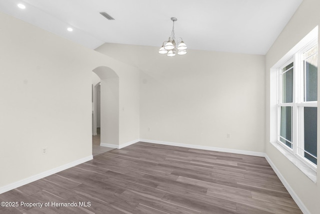 empty room featuring a notable chandelier, vaulted ceiling, and dark hardwood / wood-style floors