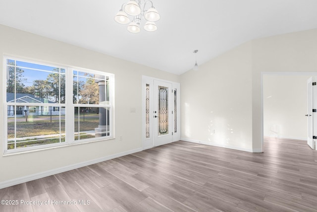 unfurnished living room featuring an inviting chandelier, wood-type flooring, and vaulted ceiling