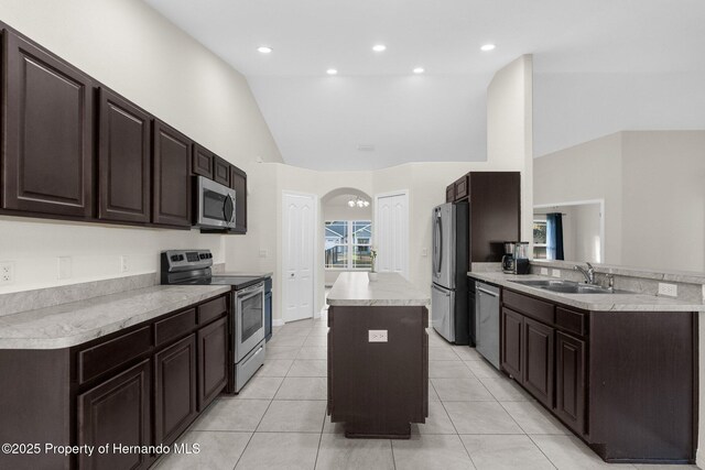 kitchen with vaulted ceiling, a kitchen island, sink, light tile patterned floors, and stainless steel appliances