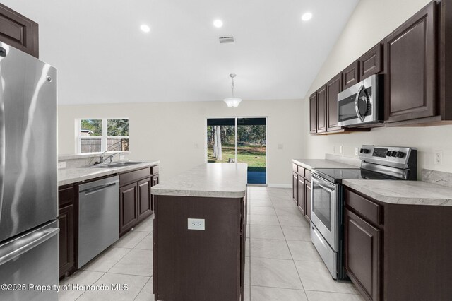 kitchen with hanging light fixtures, a kitchen island, light tile patterned flooring, and appliances with stainless steel finishes