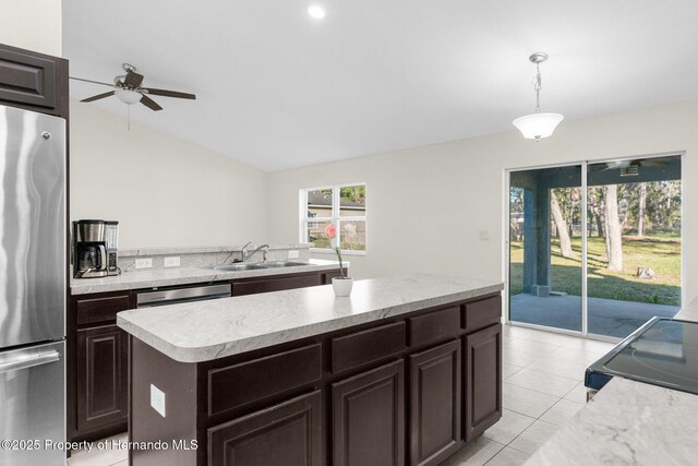 kitchen with pendant lighting, stainless steel refrigerator, sink, a center island, and electric range