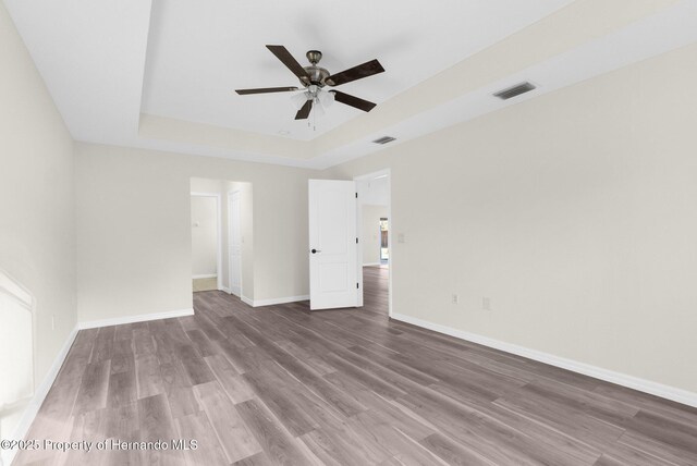 unfurnished room with hardwood / wood-style flooring, ceiling fan, and a tray ceiling