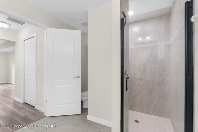 bathroom featuring tiled shower, tile patterned floors, and toilet