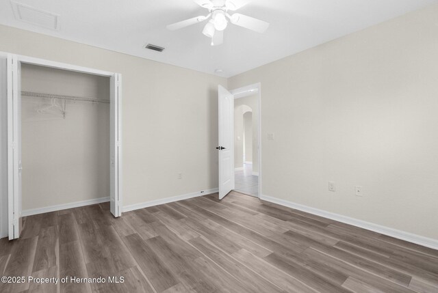 unfurnished bedroom with hardwood / wood-style flooring, ceiling fan, and a closet