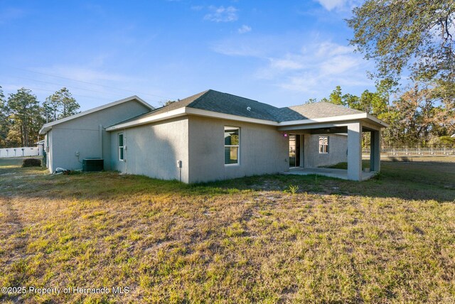 back of property featuring central AC unit and a lawn