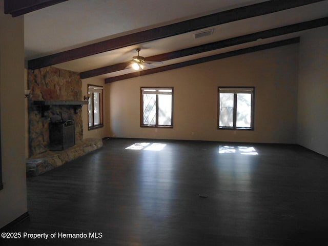 unfurnished living room featuring lofted ceiling with beams, a stone fireplace, dark hardwood / wood-style floors, and ceiling fan