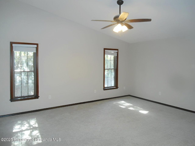 empty room featuring ceiling fan, lofted ceiling, a healthy amount of sunlight, and carpet floors