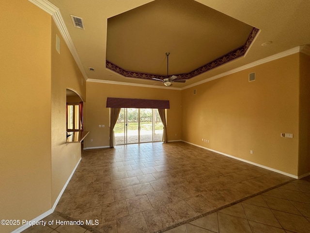 empty room with a raised ceiling, ornamental molding, and ceiling fan