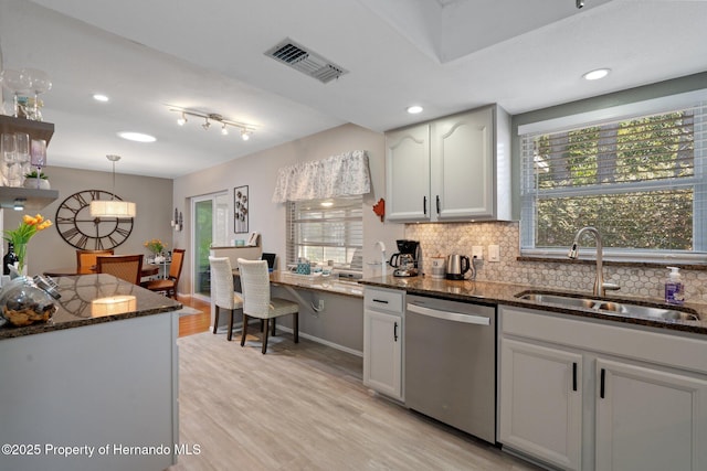 kitchen featuring sink, white cabinetry, hanging light fixtures, stainless steel dishwasher, and decorative backsplash