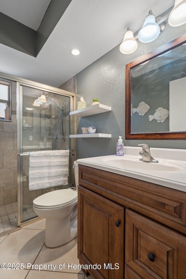 bathroom with an enclosed shower, vanity, tile patterned flooring, and toilet