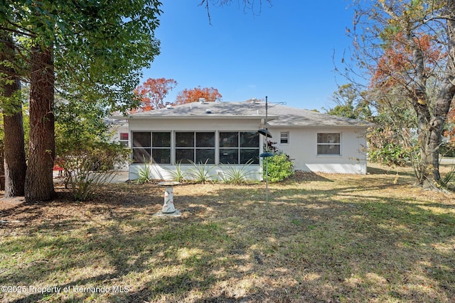 back of property featuring a yard and a sunroom