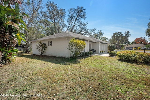 view of side of home featuring a garage and a lawn