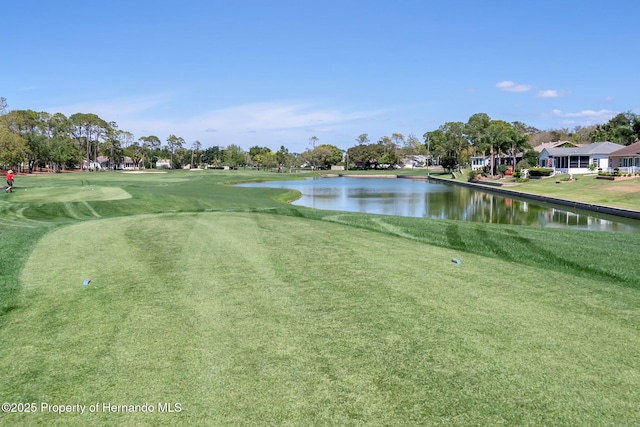 surrounding community with a water view and a lawn