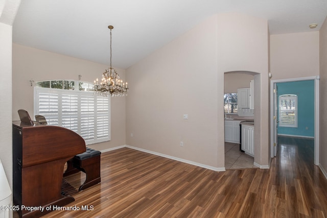 dining space featuring lofted ceiling, an inviting chandelier, and dark hardwood / wood-style flooring