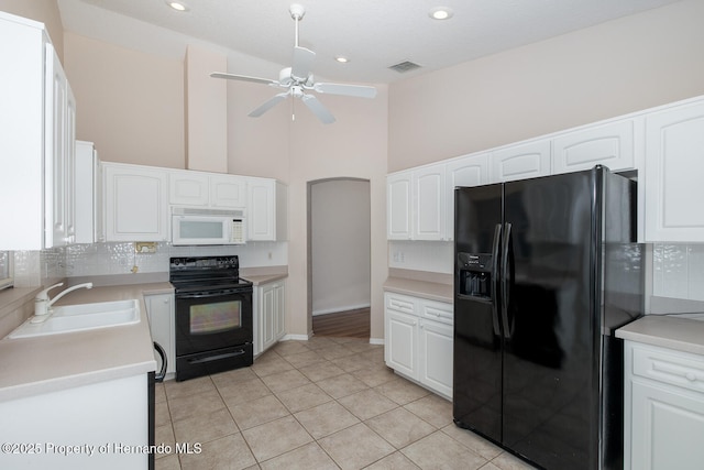 kitchen with tasteful backsplash, white cabinets, sink, and black appliances