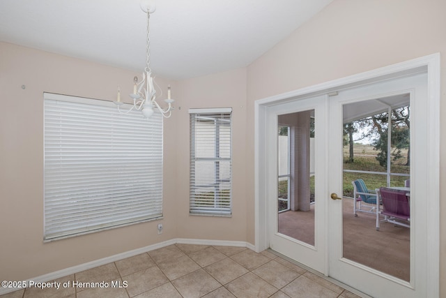 unfurnished dining area with light tile patterned floors, an inviting chandelier, and french doors