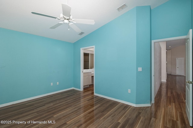 unfurnished bedroom with lofted ceiling, connected bathroom, dark hardwood / wood-style flooring, and ceiling fan