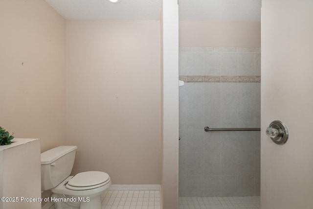 bathroom featuring toilet, tile patterned flooring, and a tile shower