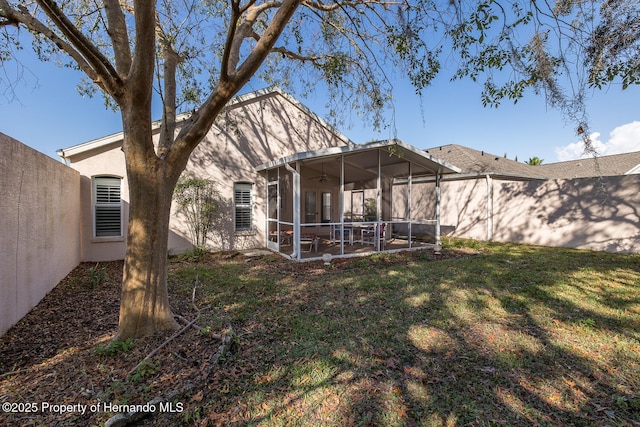 rear view of property with a lawn, a sunroom, and a patio