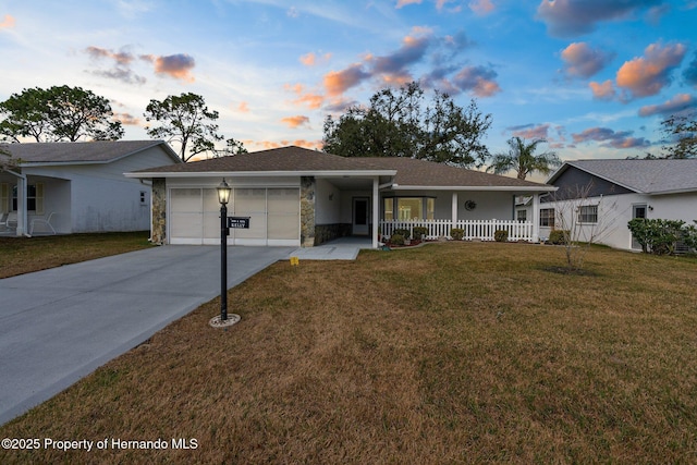 ranch-style house featuring a porch, a garage, and a lawn